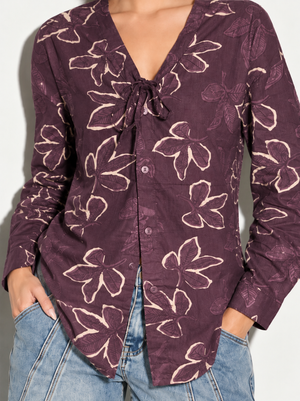 Close-up of Leher mauve shirt with cream outline florals, tie-neck V-neckline and button front